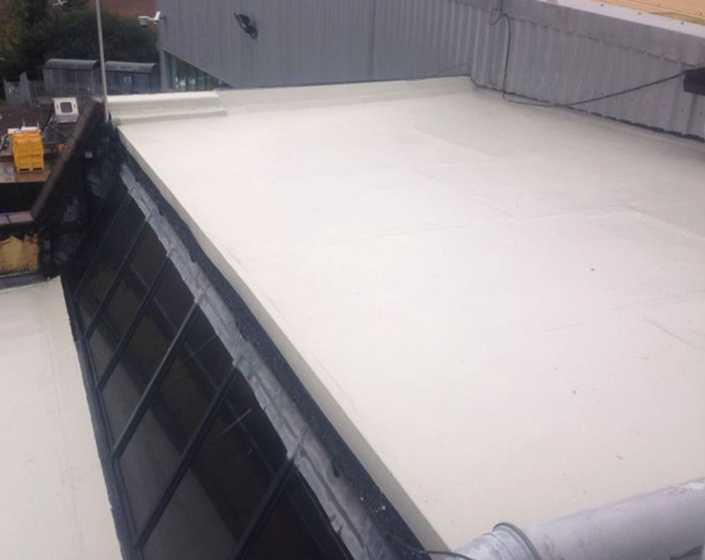 Pale grey liquid applied membrane over an existing flat roof, with upstands and rooflight encapsulated